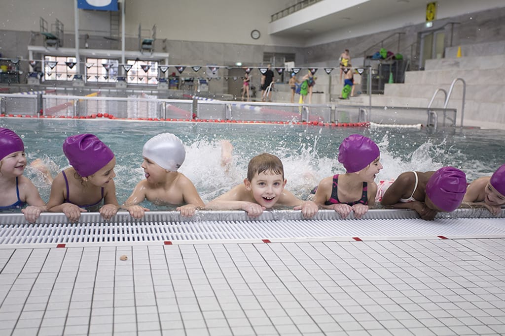 Kinder lernen schwimmen am Beckenrand