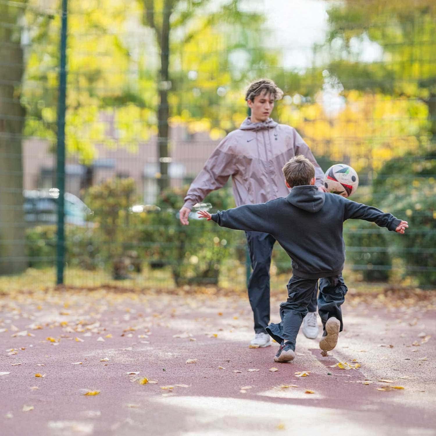 Zwei Jungen spielen Fußball auf einem herbstlichen Bolzplatz